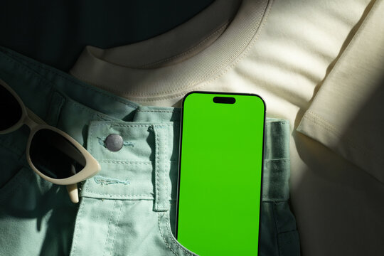 Flat lay of casual summer outfit with smartphone and sunglasses