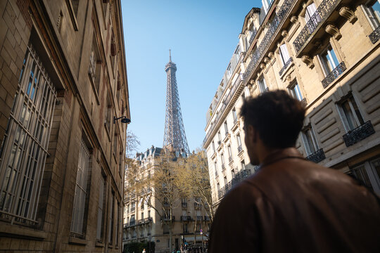 Man looking at the Eiffel Tower from a Parisian street