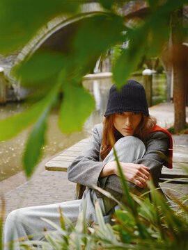 Woman Sitting by a River in a City Park During the Day