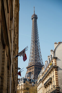 Eiffel Tower framed by Parisian buildings and French flags