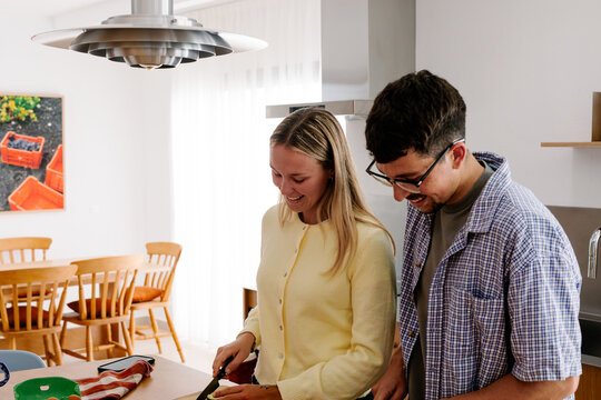 A smiling couple prepares food together at a kitchen island.