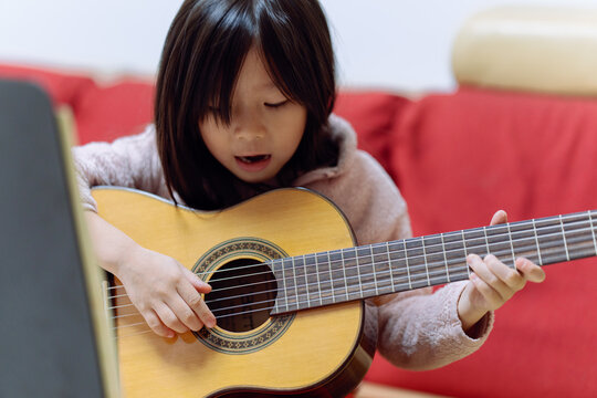 Young Girl Plays Guitar During Music Practice at Home