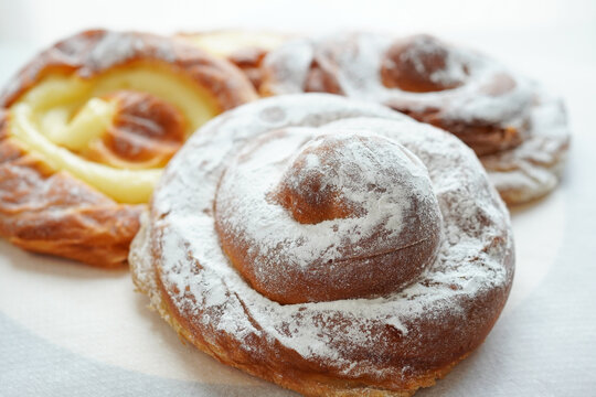 Selection of delicious Spanish ensaimada buns with custard and powdered sugar