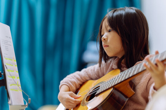 Child Learns to Play Guitar Indoors During Morning Practice