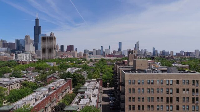 Chicago neighborhood presenting city skyline with Sears Tower, modern downtown buildings, and residential real estate during spring season under clear blue sky