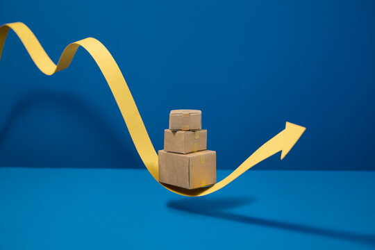 Cardboard boxes stacked on a yellow arrow indicating growth on blue