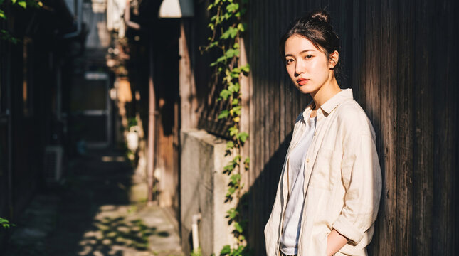 ノスタルジックな路地裏に佇む若い日本人女性 夏の日差しと影