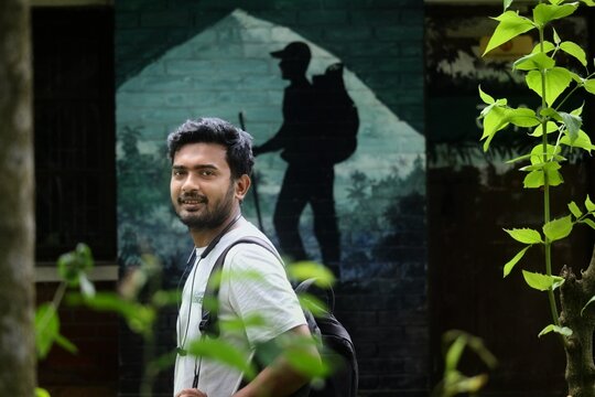 Creative composition of a man looking back with a hiker illustration background and green leaves frame