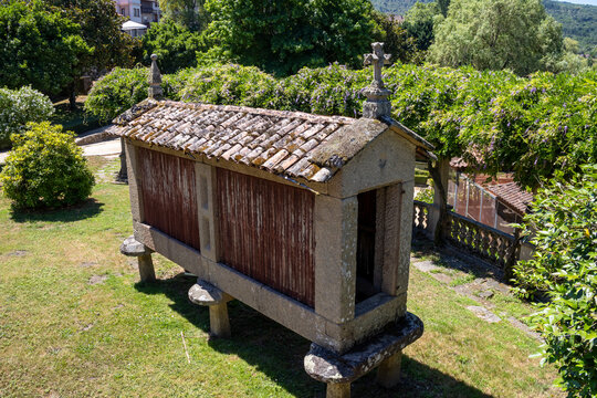 Historic traditional horreo granary built of stone granite and wood in Allariz, Ourense, Galicia, Spain. Elevated high angle view of the ancient rural structure on a green grass garden field.