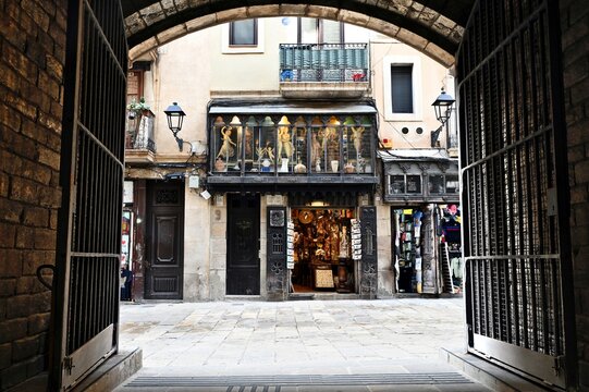narrow alley in the Gothic Quarter in Barcelona, Spain. antique store display window. decorative old stone building elevation. view from under a stone gateway arch. travel and tourism concept.