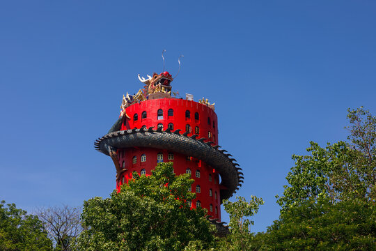 Giant dragon wrapped around the red tower of Wat Sam Phran temple in Thailand