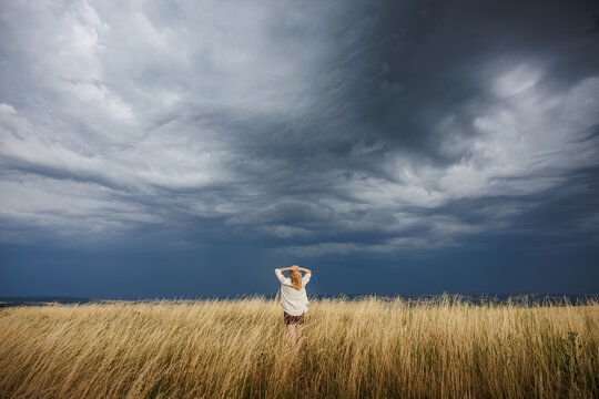 Thunderstorm and rain is coming. Woman watching fast moving storm clouds and extreme summer weather phenomenon