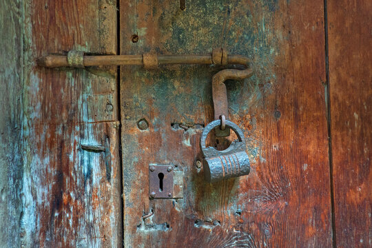 Old sliding bolt lock with padlock on antique wooden door