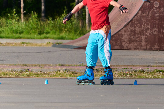 Young man rollerblading skillfully through blue cones on sunny outdoor track