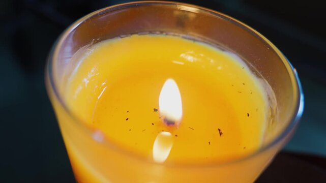 Burning yellow candle flame in glass jar container