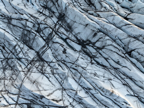 Aerial view of the crevassed ice surface and dark volcanic ash deposits of Svinafellsjokull glacier in Hornafjordur, Iceland.