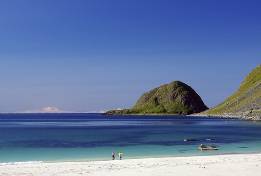 Transparent clear water with two single people on a sandy beach, barren green rocks, dream beach, summer, Haukland, Leknes, Lofoten, Nordland, Norway