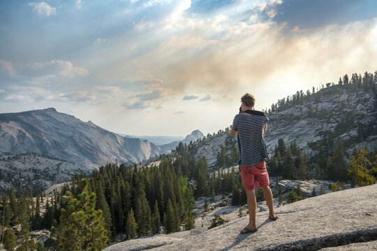 Young man, tourist photographing High Sierra, Olmsted Point, Yosemite National Park, California, USA