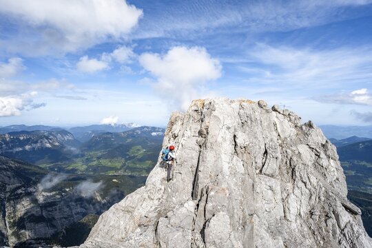 Female mountaineer climbing a via ferrata secured with a steel cable, narrow rocky ridge, Watzmann crossing to the Watzmann Mittelspitze, Berchtesgaden National Park, Berchtesgaden Alps, Bavaria, Germany