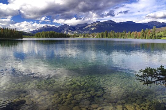 Crystal clear lake surrounded by mountains, clouds and forests with a clear sky, Jasper, Jasper National Park, Icefields Parkway, Alberta, Canada