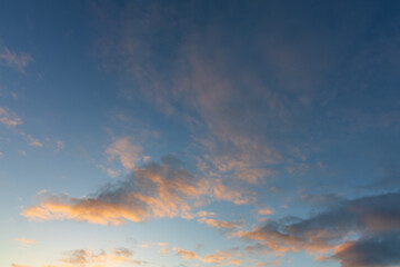 Fototapeta premium Clear Blue Sky with Wispy Orange Lit Clouds at Dawn Background