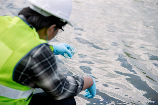 Ecologist examining water sample with flask near water surface for environmental research and analysis