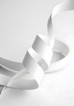 Abstract white ribbon swirling in a graceful curve against a bright studio background