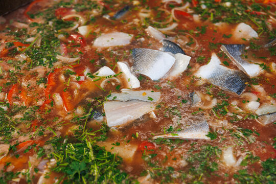 Traditional fish soup with fresh tomatoes being cooked outdoors at a vibrant culinary food festival
