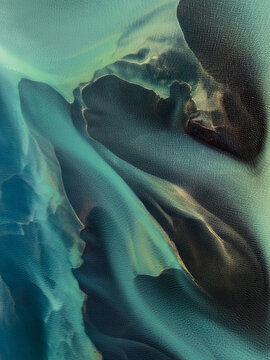 Aerial view of glacial river patterns with turquoise water and dark sediment deposits in Iceland.