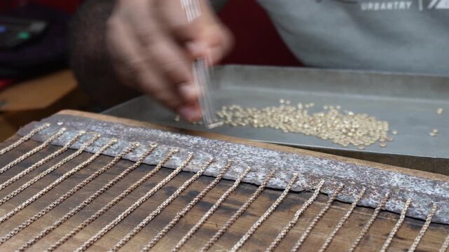 Artisan assembling intricate silver chain with precision