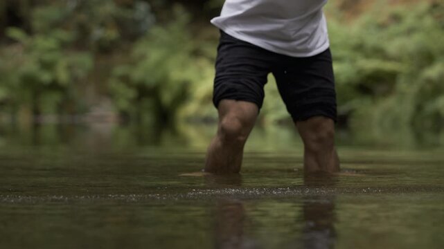 Low Shot Of Man Swinging Wet Board Over Surface Of Shallow Stream