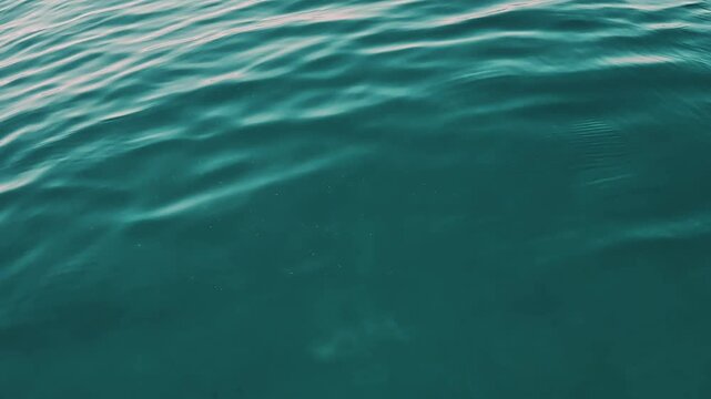 V&iacute;deo de la superficie del mar en primer plano, con agua turquesa, ondulaciones suaves y textura natural del movimiento del agua. Imagen abstracta y minimalista, &uacute;til para conceptos de calma, verano, 