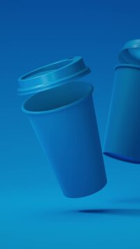 Two minimalist blue blank takeaway coffee cups floating above a blue background in a seamless 3D loop. Vertical video.