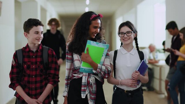 Happy friends excited teen students walking together in school corridor during break. Group portrait of pretty friendly children having a good time together at school.