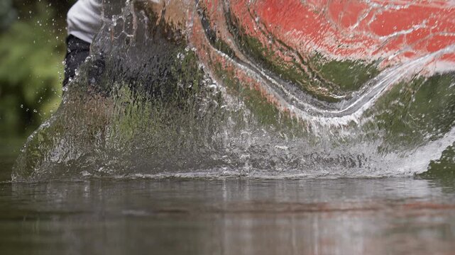 Man Standing in Shallow Water And Making A Splash With Large Board - Low, Slow Motion Shot
