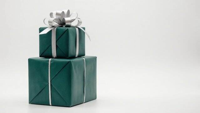 Two stacked green gift boxes with silver ribbons isolated on white background