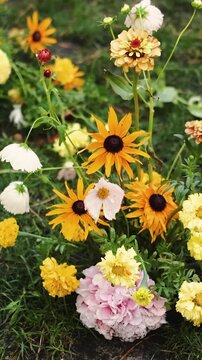 Vertical video. Floral wedding arrangement with garden flowers at an outdoor ceremony venue.
