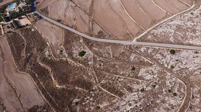 Ix-Xini, Gozo, Malta - aerial view of plowed agricultural fields with small water bodies in a rural landscape showing neutral patterns and textures in brown and green tones during daylight. . High