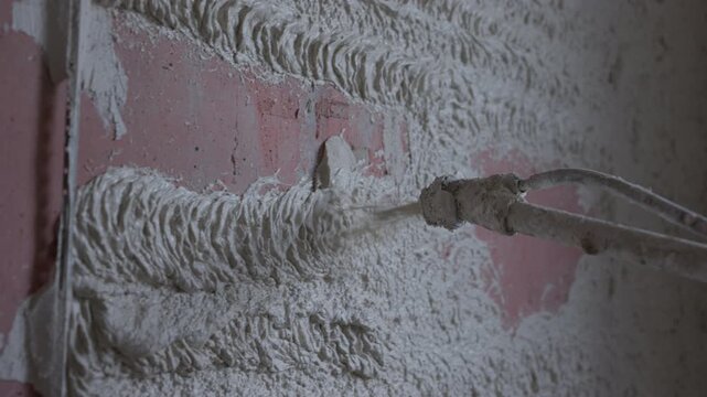 Spraying plaster onto wall with plastering machine during interior construction