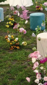 Vertical video. Wedding seating with elegant poufs and floral decor on grass for an outdoor ceremony.