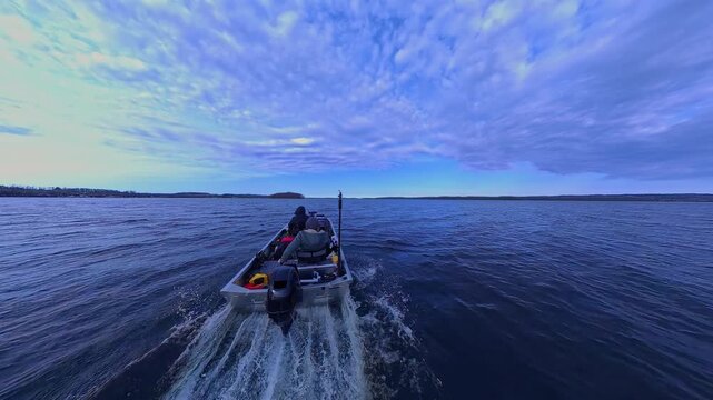 Two anglers cruising at large lake during cloudy spring day looking for fishing spot. Peaceful retreat from the busy life routine. Couple relaxing in utility boat, trolling on beautiful lake water.