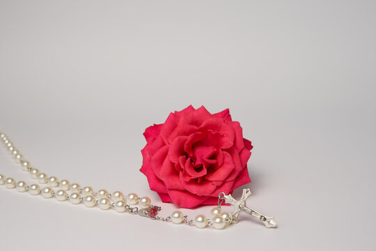Rosary beads with pink rose flower on light background, Christian prayer and faith concept with copy space