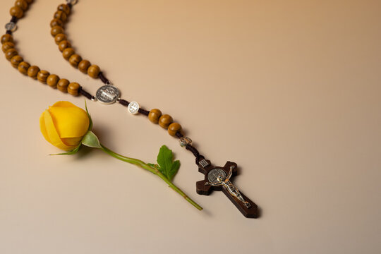 Rosary beads with yellow rose on light background, Christian prayer and faith concept with copy space