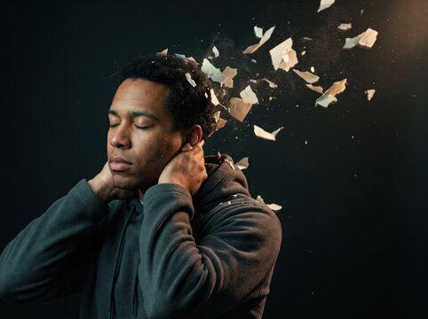 Man with eyes closed dissolving into paper fragments, memory loss
