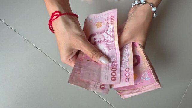 태국 지폐 바트화를 두 손으로 정성스럽게 세고 있는 모습
