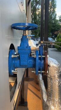 Blue industrial gate valve with condensation on water pipeline
