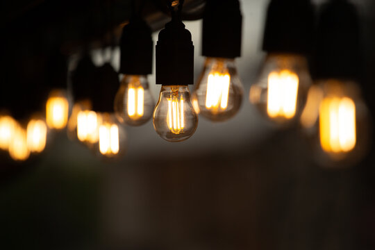 Cozy warm string lights with glowing Edison bulbs on a dark blurred background
