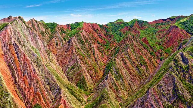 Colorful Danxia landform mountain range with vibrant red and green slopes in Xinjiang, China.