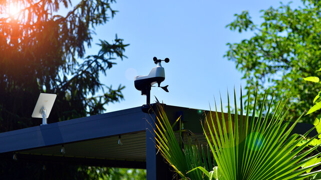 Weather station sensor installed on a pergola rooftop against a clear blue sky