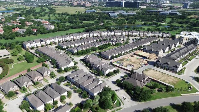 Vue Las Colinas residential rows nestle against mature green zones. Dense housing clusters feature dark shingles under sun drenched sky conditions found across northern suburban area of Irving TX